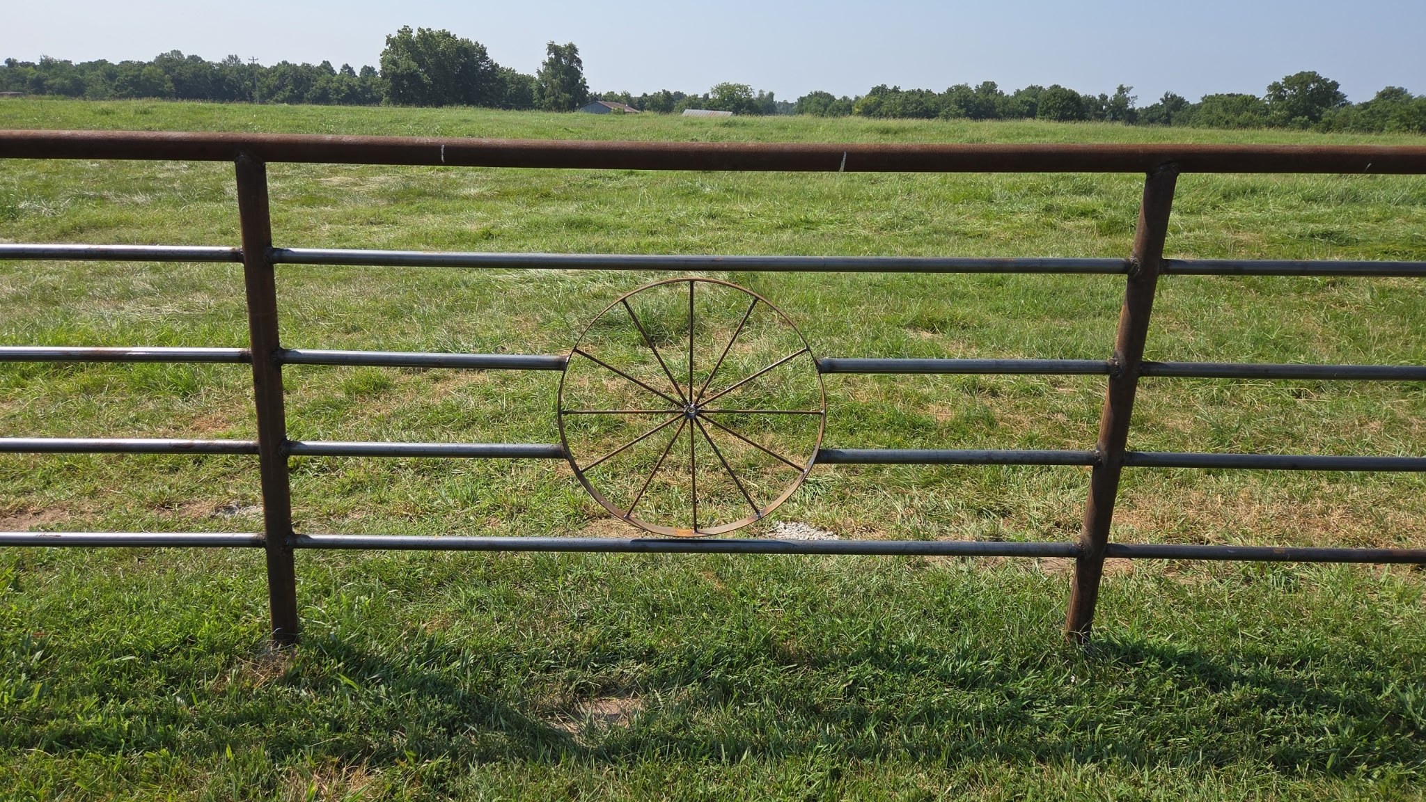 Pipe fence gate with decorative wagon wheel